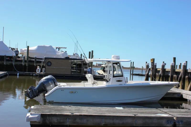 Slide: The Image of 2023 Sea Hunt Gamefish 27 with Coffin Box docked at a marina under clear blue skies. - 10