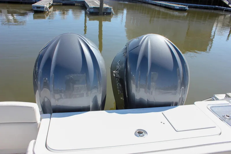 Slide: The Image of Twin outboard engines on a 2023 Sea Hunt Gamefish 27 with Coffin Box, docked in calm water. - 19