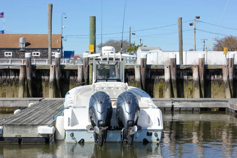 Slide: The Image of 2023 Sea Hunt Gamefish 27 with Coffin Box docked, featuring dual outboard engines. - 2