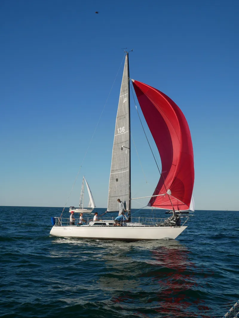 Slide: The Image of Sailboat Abbott 33 (1987) with red spinnaker sailing on open water. - 2