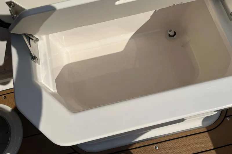 Slide: The Image of Open storage compartment on 2025 Chaparral 267 SSX boat, featuring a clean, white interior. - 16