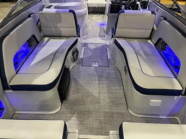 Slide: The Image of 2025 Crownline Eclipse E305 boat interior with plush seating and ambient blue lighting. - 2