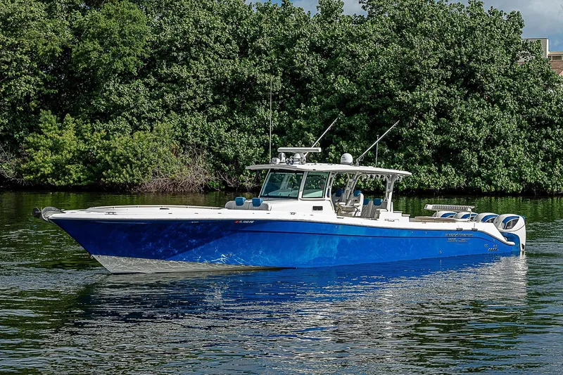 Slide: The Image of 2016 HCB 53 Sueños boat with blue hull on calm water, lush greenery background. - 1
