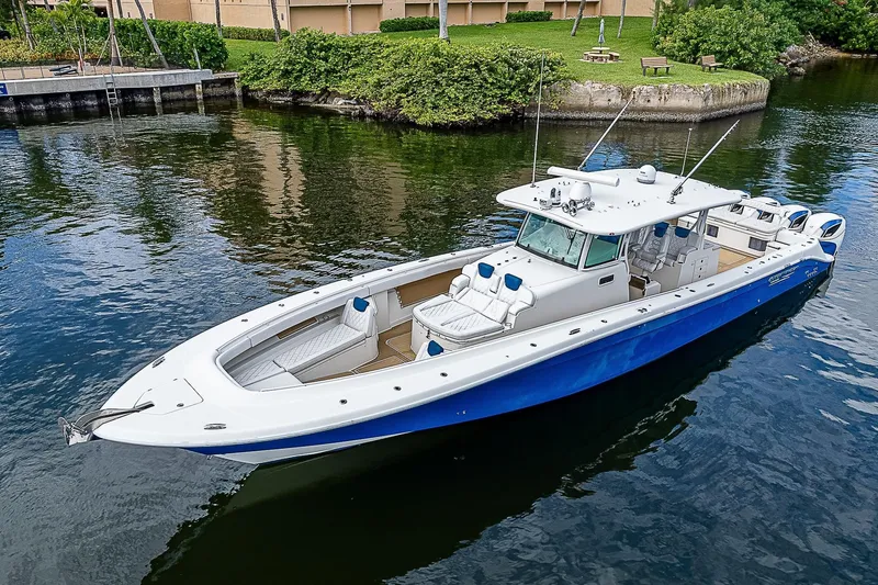 Slide: The Image of HCB 53 Sueños 2016 boat with blue hull, docked in calm waters, surrounded by greenery. - 5