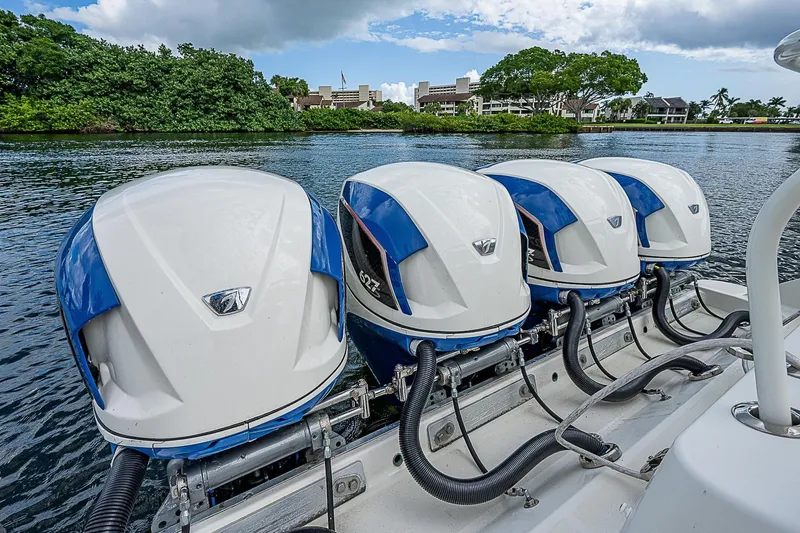 Slide: The Image of Four powerful outboard engines on a 2016 HCB 53 Sueños boat, docked by lush greenery. - 8