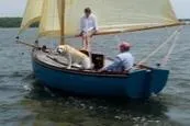 Slide: The Image of A Golant Gaffer Cutter Rig sailboat from 2009 with two people and a dog on board. - 2