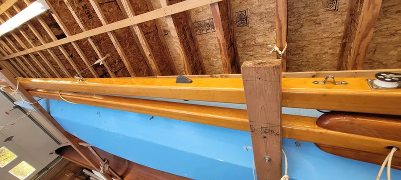 Slide: The Image of Golant Gaffer Cutter Rig 2009 sailboat in storage, showcasing wooden mast and blue hull. - 29