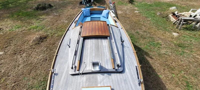 Slide: The Image of 2009 Golant Gaffer Cutter Rig sailboat on grass, featuring wooden deck and blue cushions. - 34
