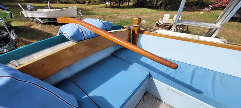 Slide: The Image of Golant Gaffer Cutter Rig 2009 with blue cushioned seating and wooden tiller in a grassy area. - 6