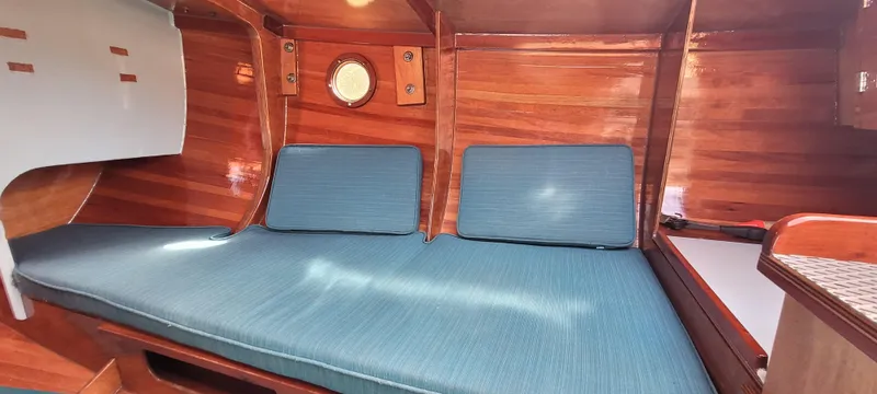Slide: The Image of Cozy interior of 2009 Golant Gaffer Cutter Rig with blue cushions and wooden finish. - 9