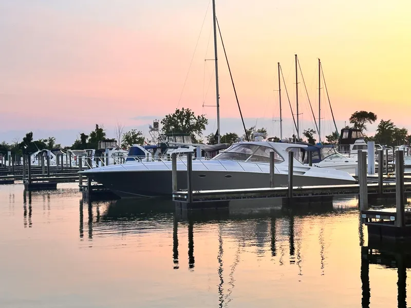 Slide: The Image of 2006 Fountain 48 Express Cruiser docked at sunset, serene marina setting. - 2