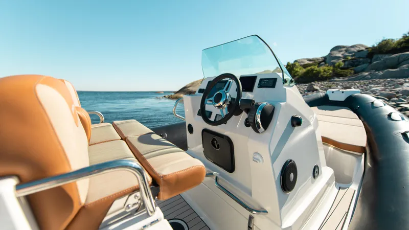 Slide: The Image of 2025 Zodiac Medline 7.5 boat interior with steering wheel, ocean view, and rocky shoreline. - 11