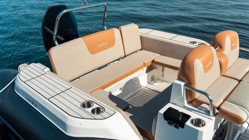 Slide: The Image of 2025 Zodiac Medline 7.5 boat interior with tan seating and cup holders on calm water. - 16