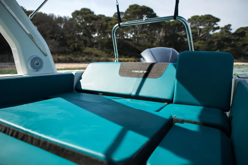 Slide: The Image of 2025 Zodiac Medline 7.5 boat interior with teal seating, near a wooded shoreline. - 6