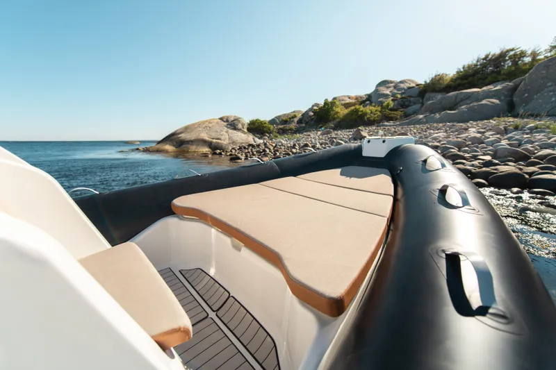 Slide: The Image of 2025 Zodiac Medline 7.5 boat on rocky shore, featuring spacious deck and scenic coastal view. - 7
