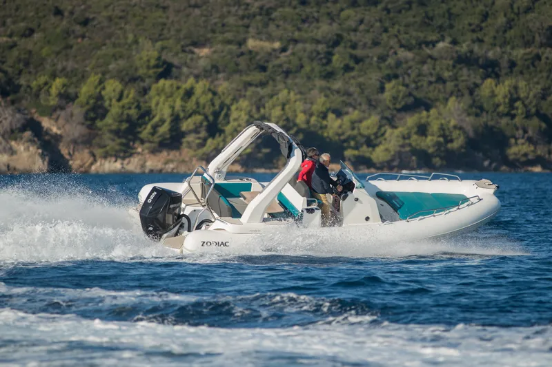 Slide: The Image of 2025 Zodiac Medline 7.5 boat cruising on water with lush green shoreline in background. - 14