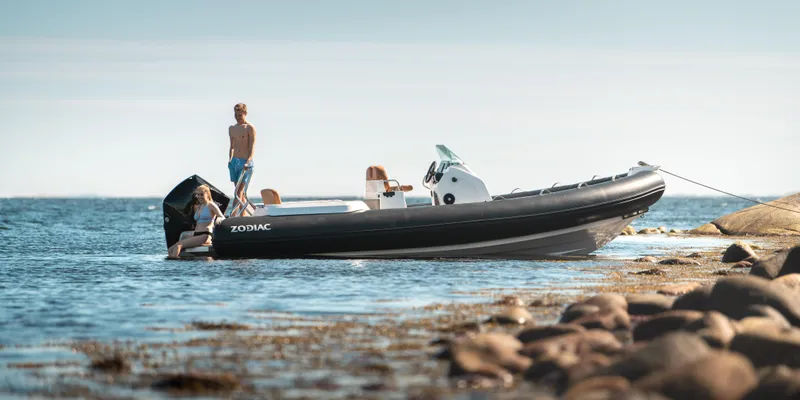 Slide: The Image of 2025 Zodiac Medline 7.5 boat anchored near rocky shore with people enjoying the water. - 22