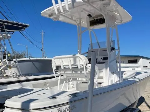 Slide: The Image of 2018 BlackJack 256 Bay boat with T-top and seating, docked under clear blue sky. - 2