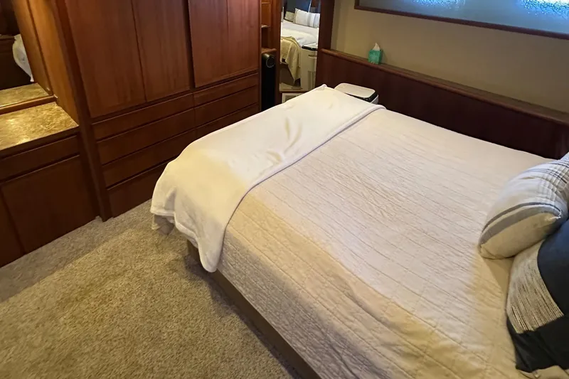 Slide: The Image of Bedroom interior of 1990 Tollycraft 57 Wide Body yacht with cozy bed and wooden cabinetry. - 16