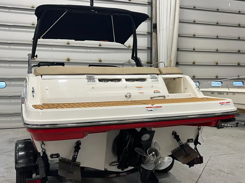 Slide: The Image of 2022 Bayliner VR5 Bowrider I/O boat in a garage, rear view with propeller visible. - 15