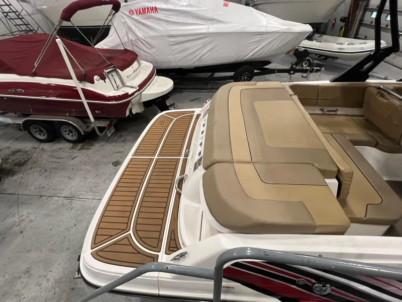 Slide: The Image of 2022 Bayliner VR5 Bowrider I/O with tan seating and wood-style deck in a showroom. - 16