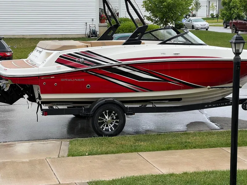 Slide: The Image of 2022 Bayliner VR5 Bowrider I/O boat with red and white design on a trailer. - 2