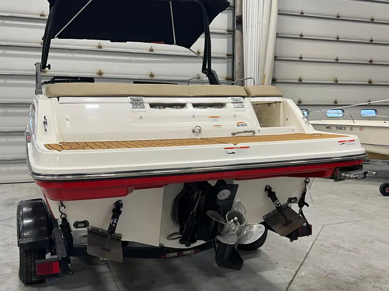Slide: The Image of 2022 Bayliner VR5 Bowrider I/O boat in a garage, rear view with propeller visible. - 25