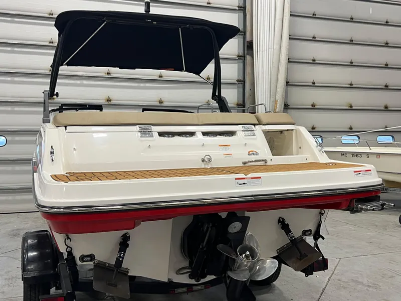 Slide: The Image of 2022 Bayliner VR5 Bowrider I/O boat in a garage, rear view with propeller visible. - 26