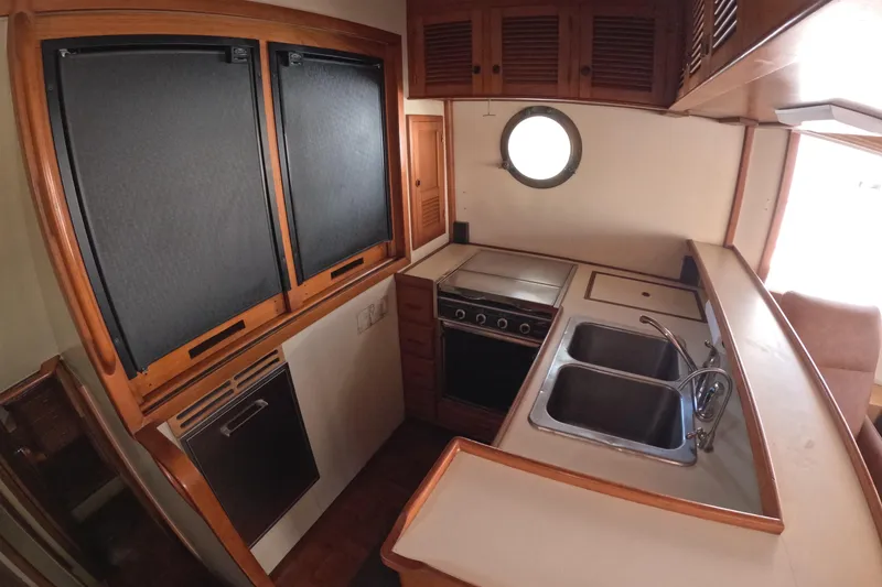 Slide: The Image of 1988 Kadey-Krogen 42 yacht kitchen with dual sinks, stove, and wooden cabinetry. - 14