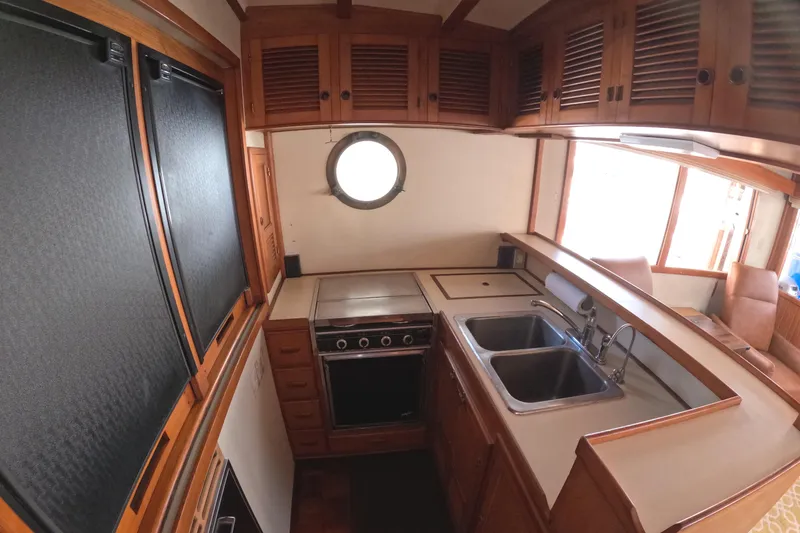 Slide: The Image of 1988 Kadey-Krogen 42 yacht kitchen with wooden cabinets, dual sinks, and a porthole window. - 15