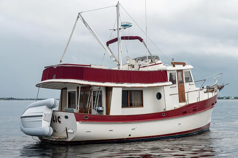 Slide: The Image of 1988 Kadey-Krogen 42 yacht with red accents on calm water. - 2