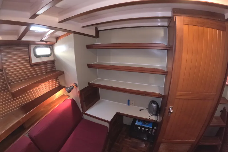 Slide: The Image of 1988 Kadey-Krogen 42 interior with wooden shelves, red seating, and a small desk area. - 28