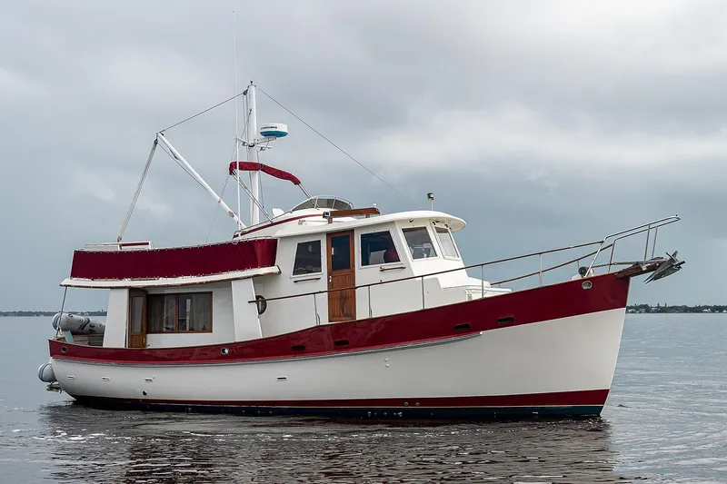 Slide: The Image of 1988 Kadey-Krogen 42 yacht on calm water, featuring a red and white design. - 7