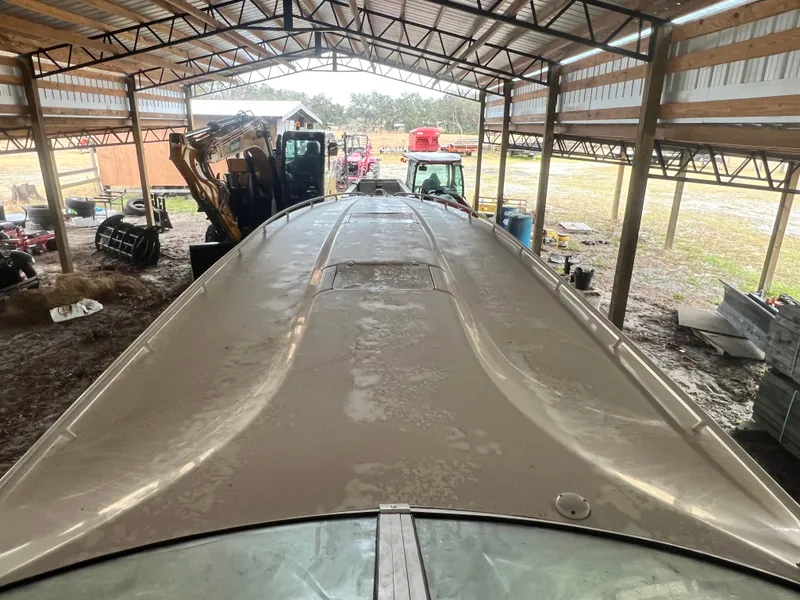 Slide: The Image of 1997 Fountain 47' Lightning boat under a metal shelter with farm equipment. - 11