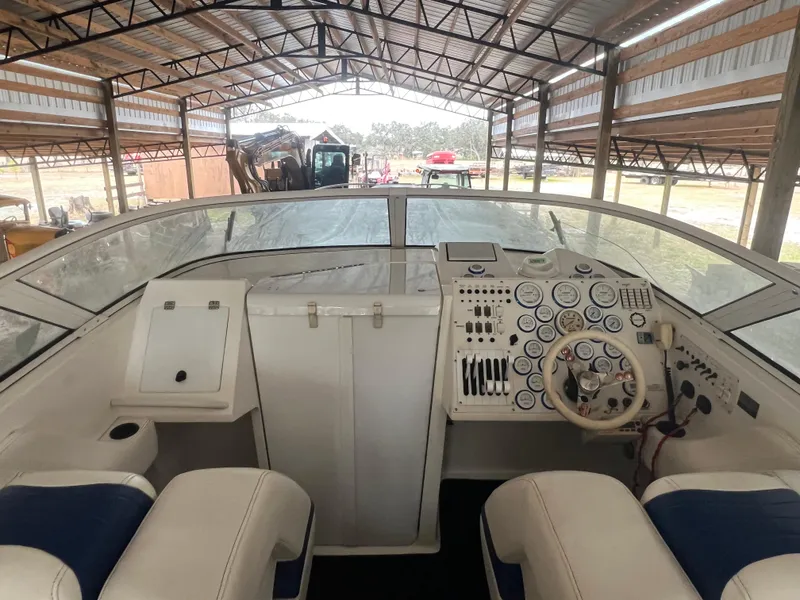 Slide: The Image of 1997 Fountain 47' Lightning boat interior with dashboard and seating in covered storage. - 13