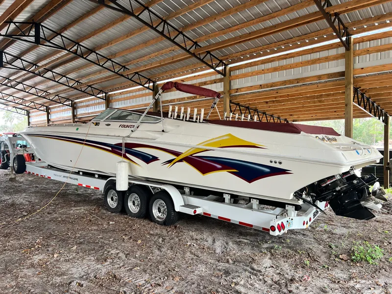 Slide: The Image of 1997 Fountain 47' Lightning speedboat under a metal shelter, on a triple-axle trailer. - 6