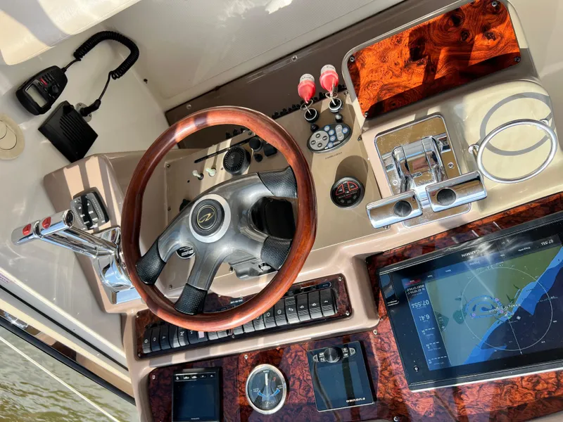 Slide: The Image of 2002 Regal Commodore 4260 helm with wood accents, steering wheel, and navigation display. - 49