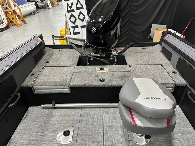 Slide: The Image of 2025 Alumacraft Trophy 175X Sport boat interior with seating and motor, in showroom. - 23