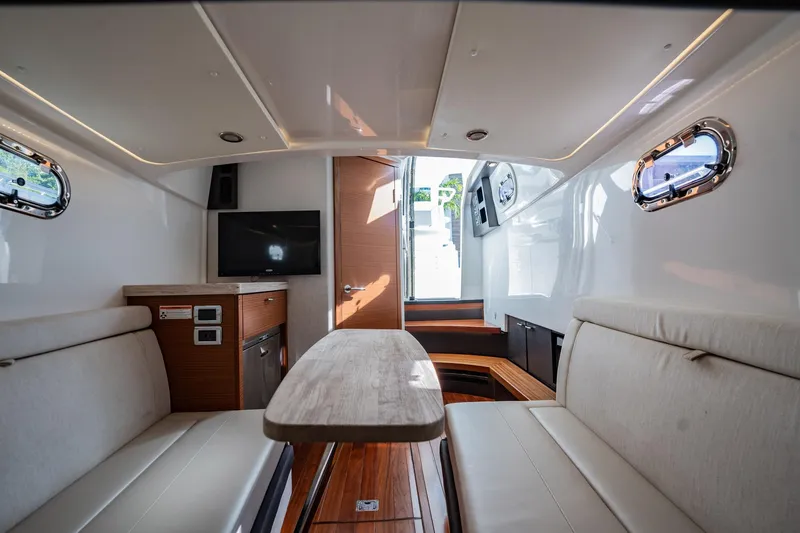 Slide: The Image of 2020 Pursuit S 408 Sport cabin interior with seating, table, and portholes. - 17