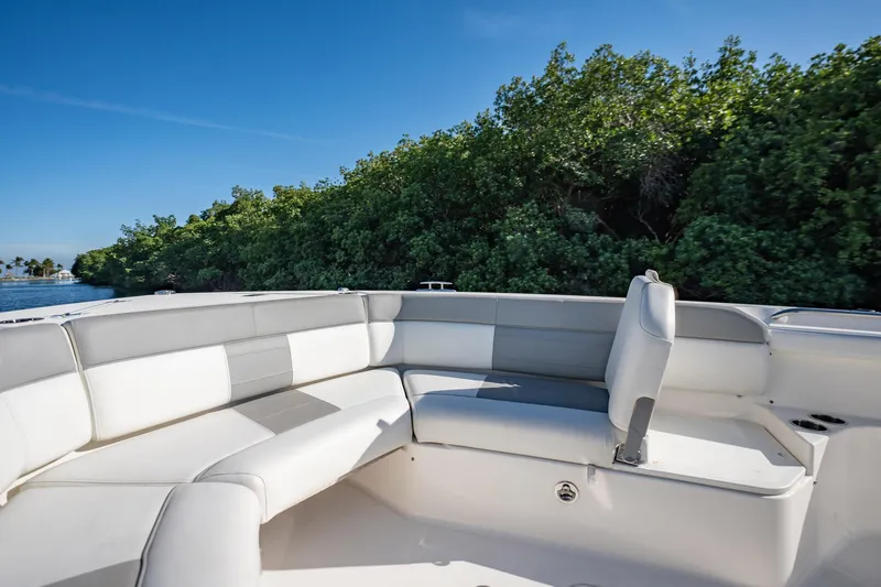 Slide: The Image of 2020 Pursuit S 408 Sport boat interior with white seating, near lush greenery. - 23