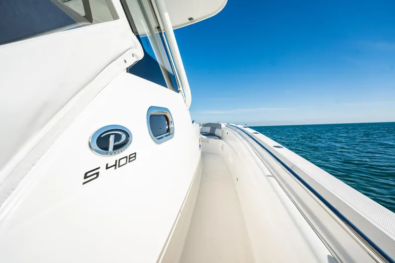 Slide: The Image of 2020 Pursuit S 408 Sport boat on open water under clear blue sky. - 28
