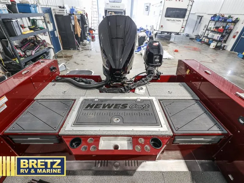 Slide: The Image of 2025 Evolution 221 boat interior with motor, Hewes Craft branding, in a marine workshop. - 23