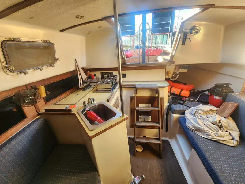 Slide: The Image of Interior of 1982 Watkins 27 Pirate Ship, featuring cozy seating and compact kitchen area. - 10