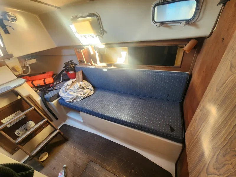 Slide: The Image of Interior of 1982 Watkins 27 Pirate Ship with blue seating and wooden accents. - 12