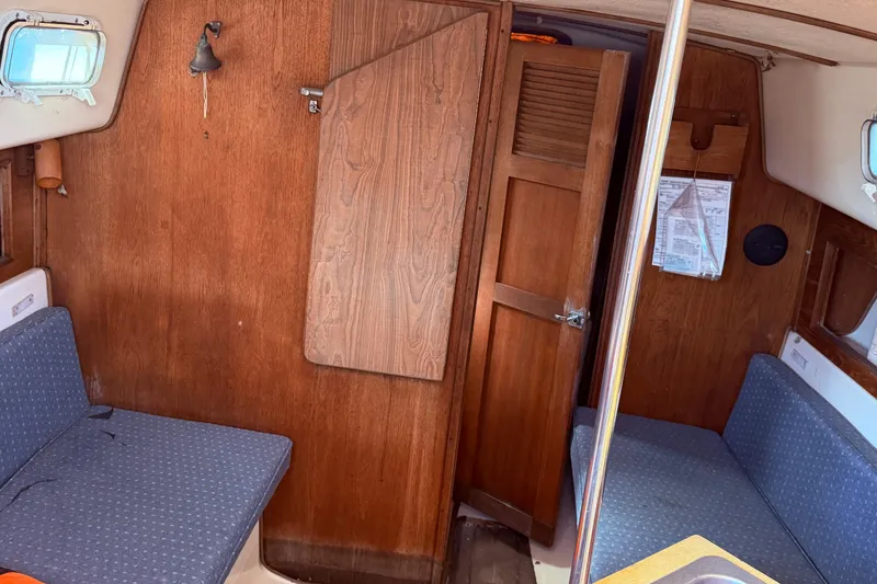 Slide: The Image of Interior of 1982 Watkins 27 Pirate Ship with wooden paneling and blue seating. - 34