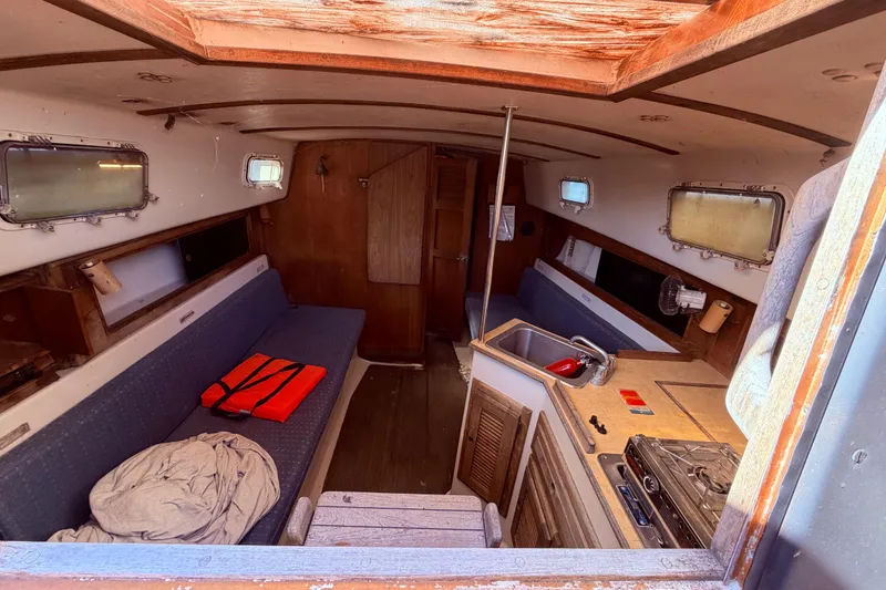 Slide: The Image of Interior of 1982 Watkins 27 Pirate Ship, featuring cozy seating and compact kitchen area. - 35