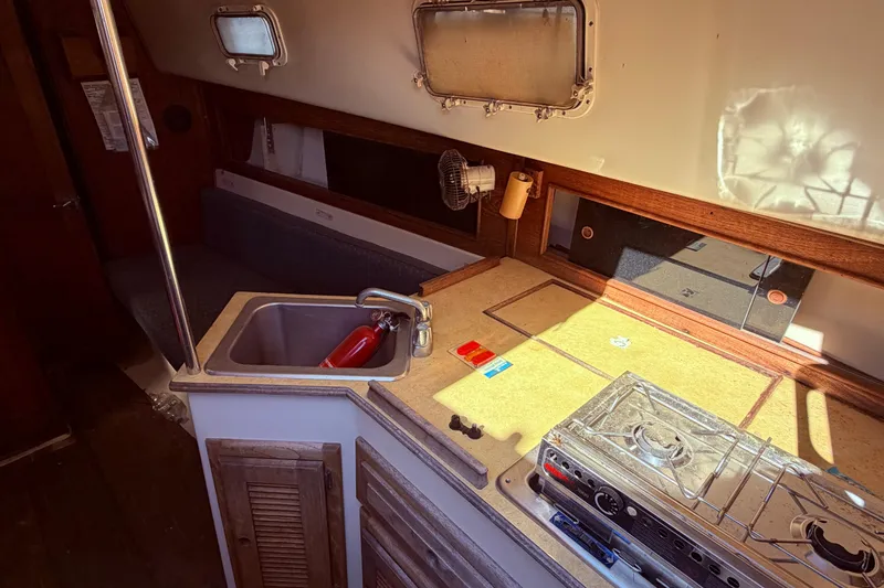 Slide: The Image of Interior of 1982 Watkins 27 Pirate Ship, featuring compact kitchen with sink and stove. - 37