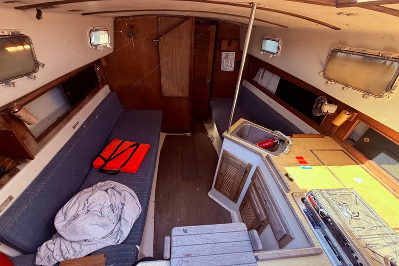 Slide: The Image of Interior of 1982 Watkins 27 Pirate Ship with cozy seating and compact kitchen area. - 38