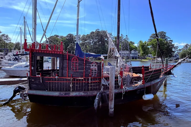 Slide: The Image of 1982 Watkins 27 Pirate Ship docked at a marina, surrounded by water and trees. - 51