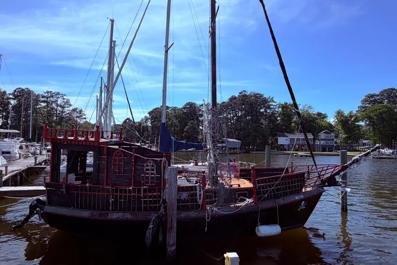 Slide: The Image of Vintage 1982 Watkins 27 Pirate Ship docked at a marina under a clear blue sky. - 52